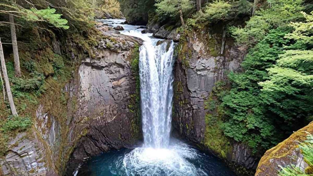 A scenic view along the Twin Falls Loop near Seattle Washington, showcasing rugged red rock formations, desert vegetation, and the vast natural beauty of the American Southwest under a clear blue sky.