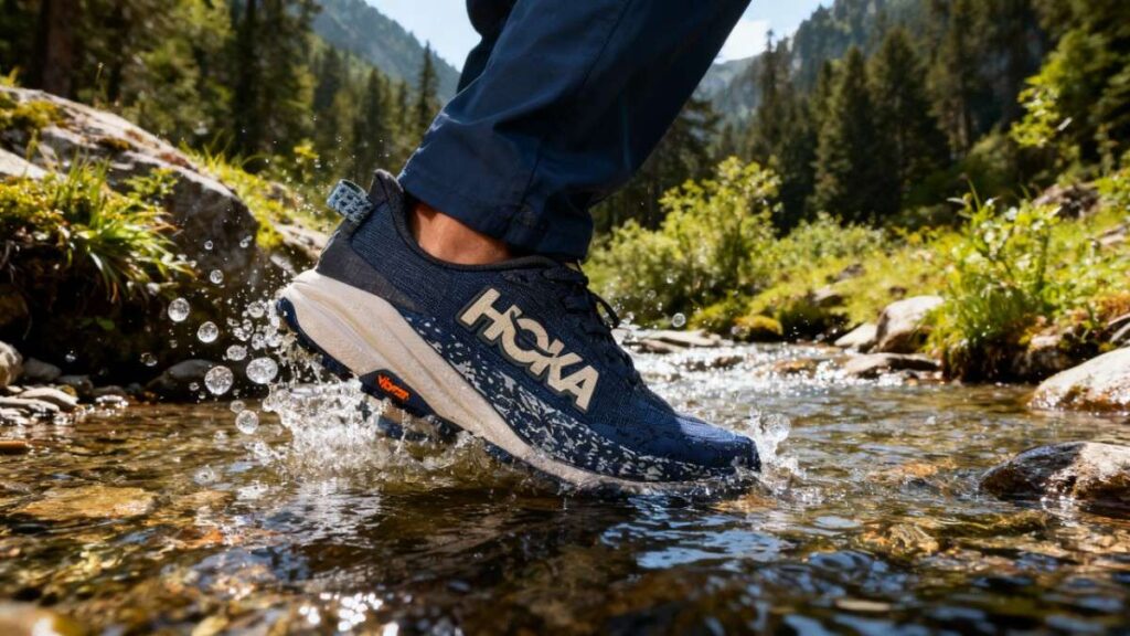 Hiker crossing water stream wearing HOKA Speedgoat 6.