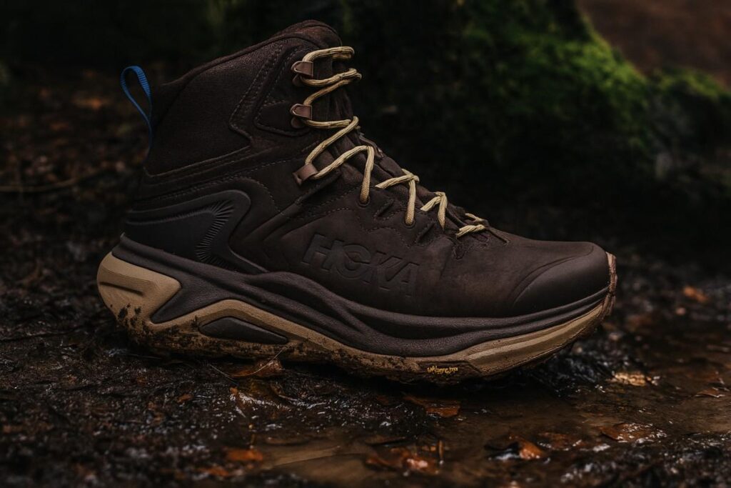 Hoka Kaha 3 GTX close-up on muddy forest trail with wet leaves — cushioned waterproof hiking boot.