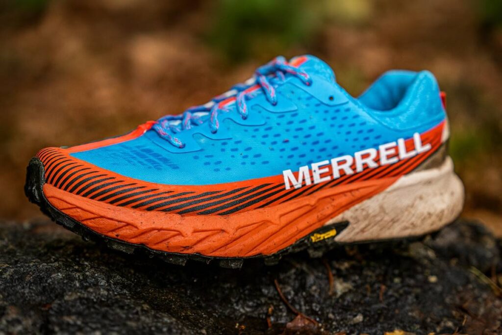 Close-up of Merrell Agility Peak 5 shoes on dusty alpine meadow trail near tree line.