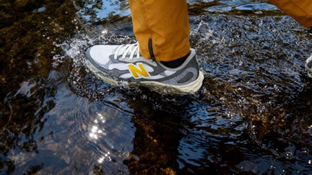 Close-up of hiker wearing NB Fresh Foam Arishi v4 and wcrossing water stream.