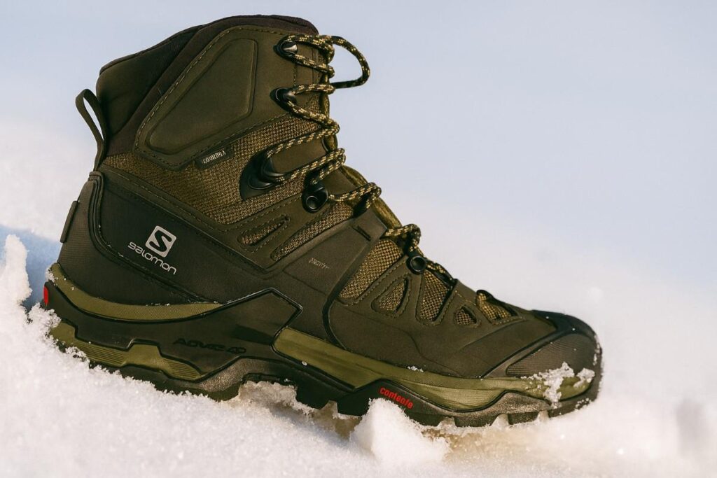 Salomon Quest 4 GTX close-up on snow-covered alpine slope — sturdy backpacking boot for winter.