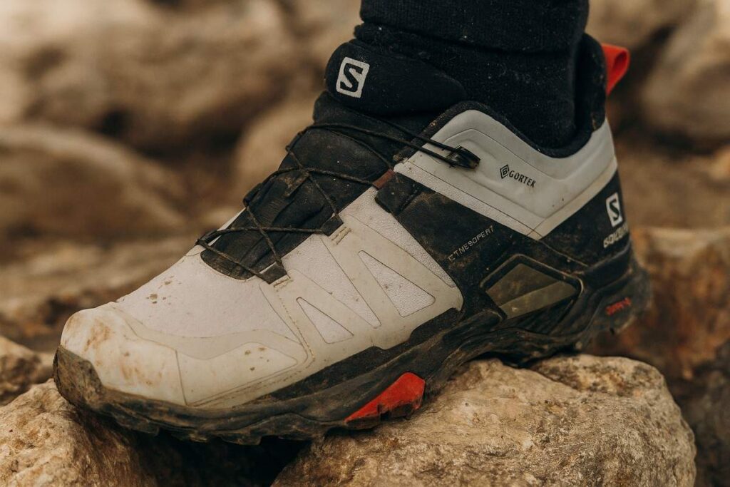 Salomon X Ultra 4 GTX close-up showing lugs on rocky uneven ground.