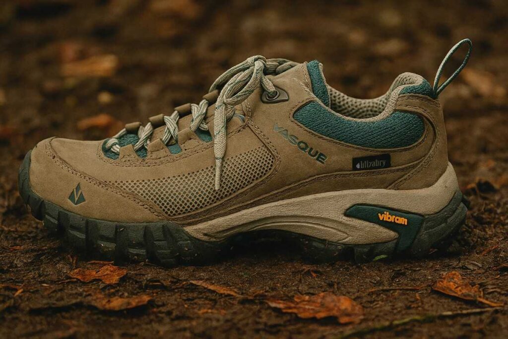 Vasque Talus Low Waterproof hiking shoes on damp dirt with autumn leaves.