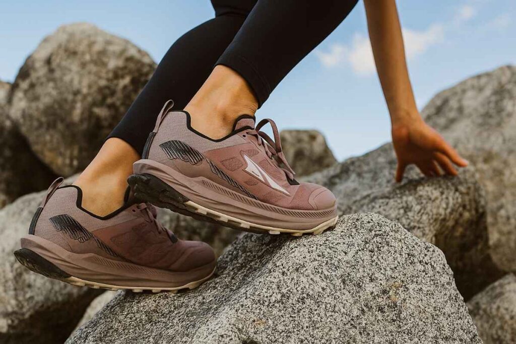 Female hiker scrambling over alpine rocks wearing Altra Lone Peak 9 trail shoes.
