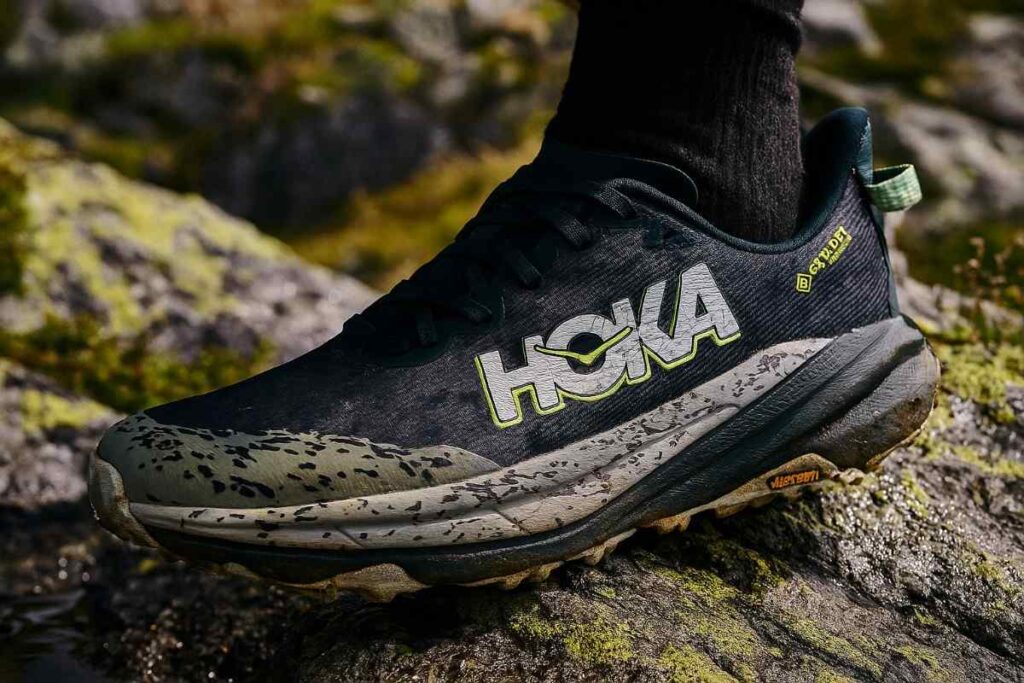 HOKA Speedgoat 6 GTX waterproof trail running shoes on rocky alpine terrain close-up.
