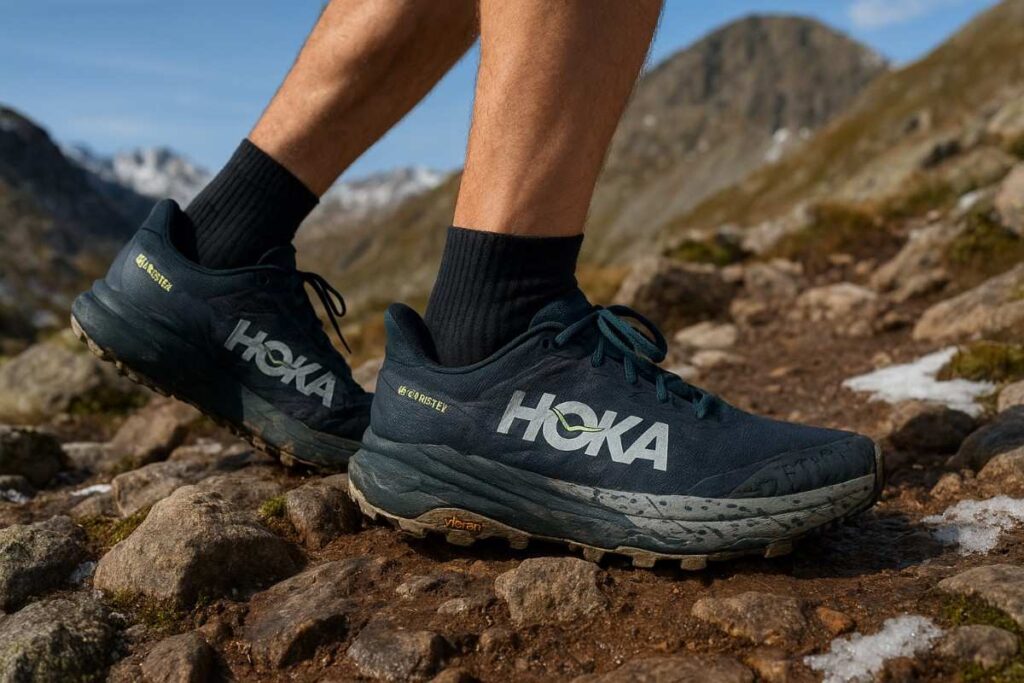 Close up of hiker wearing Hoka Speedgoat 6 GTX and trekking uphill on a rocky mount. 