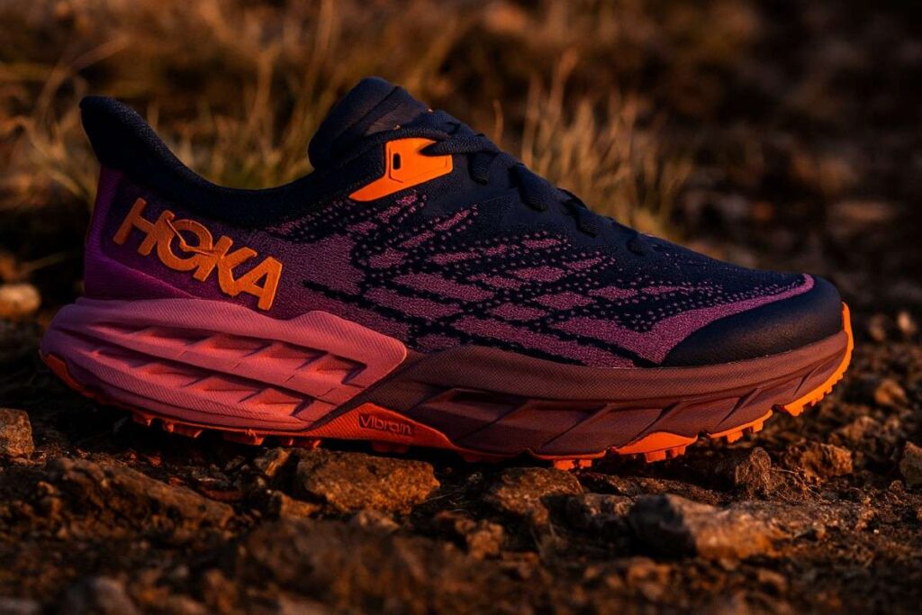 Close-up of HOKA Speedgoat 5 women’s trail running shoes on rocky alpine singletrack.