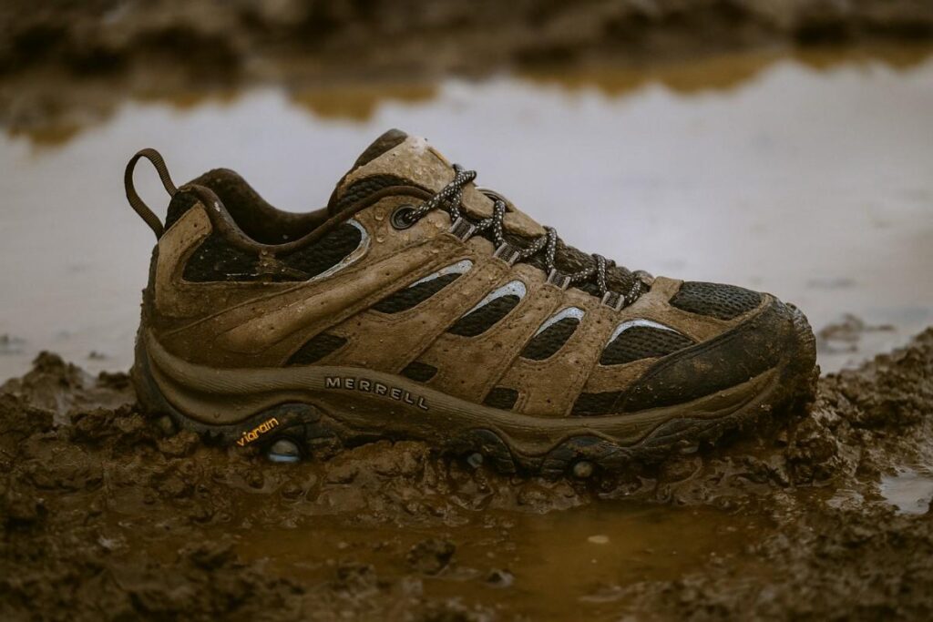 Close-up of Merrell Moab 3 Waterproof women’s shoes standing in muddy trail terrain.