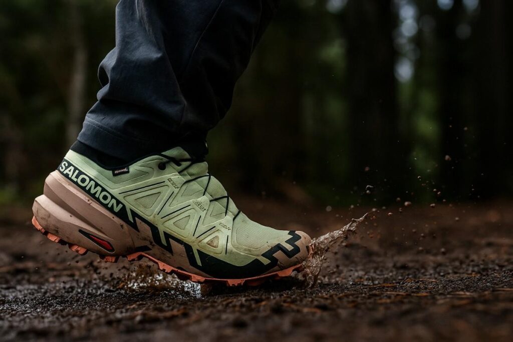Female trail runner splashing through wet muddy forest wearing Salomon Speedcross 6 GTX.