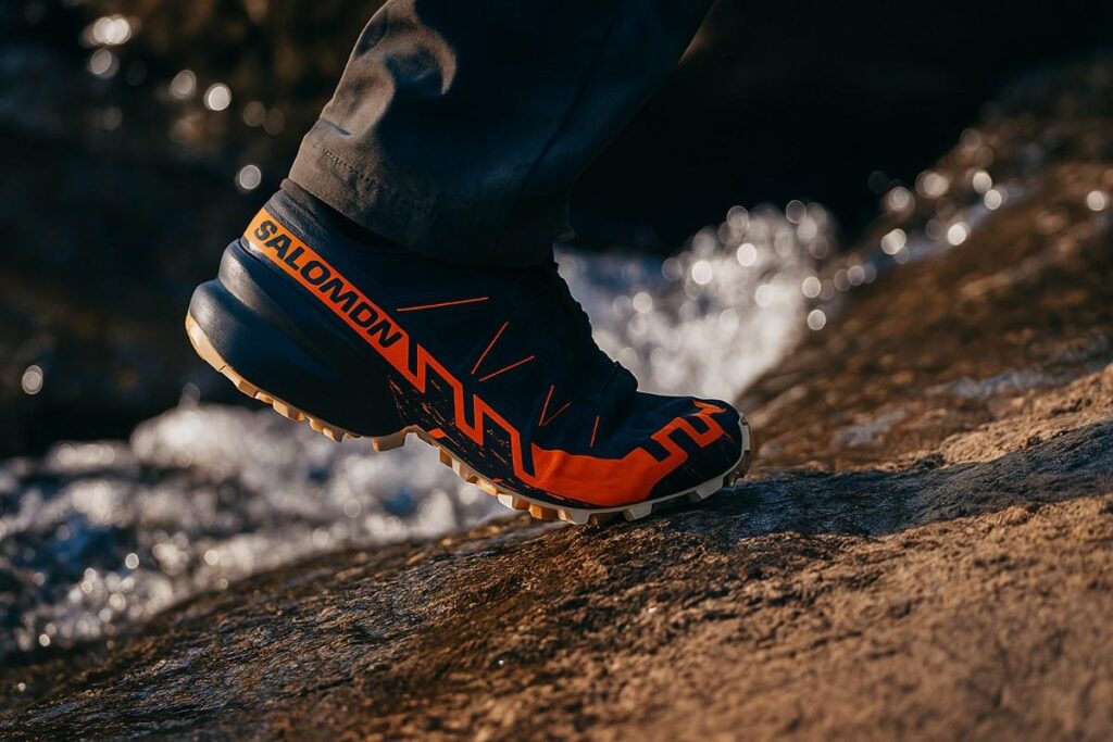 Hiker walking through rocky surface with water stream in the background.
