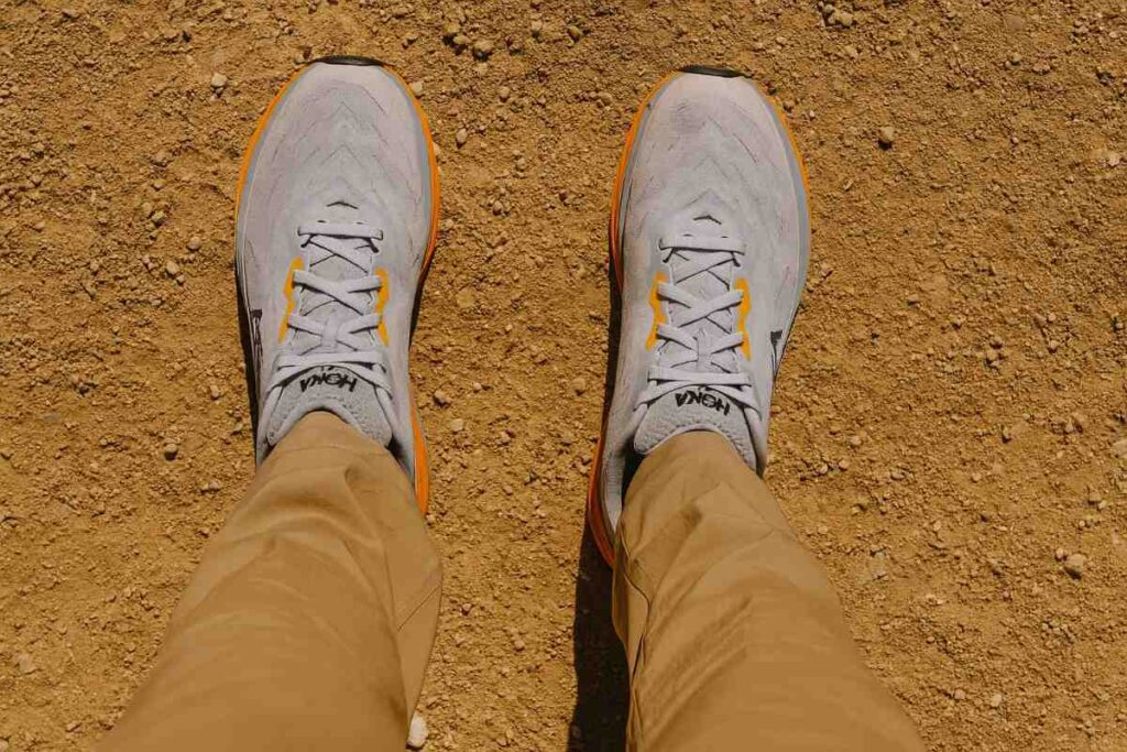 Selfie type shot of hiker wearing HOKA Arahi 6 standing on a dirt trail.