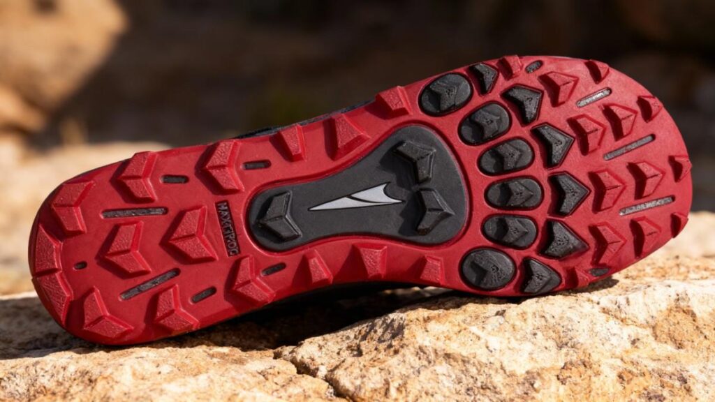 Outsole of Altra Lone Peak 6 displayed on rocky surface.