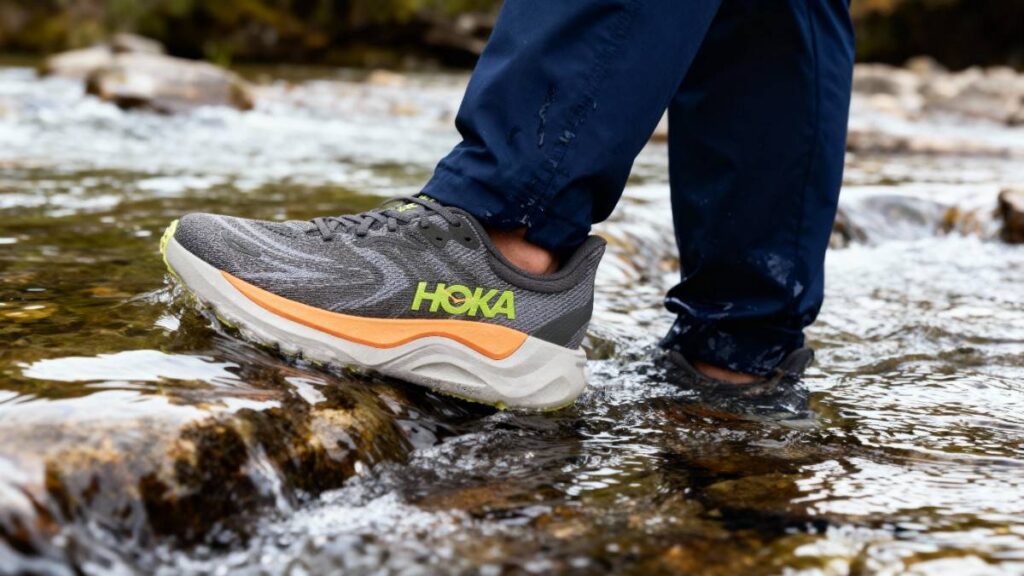 Hiker crossing water stream with Hoka Arahi 8.