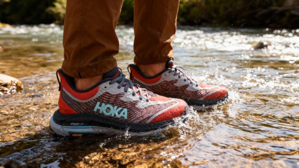 Hiker wearing HOKA Mafate Speed 4 and standing in water stream.