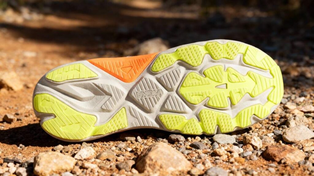 Outsole of Hoka Arahi 8 placed on a subtly rocky surface.