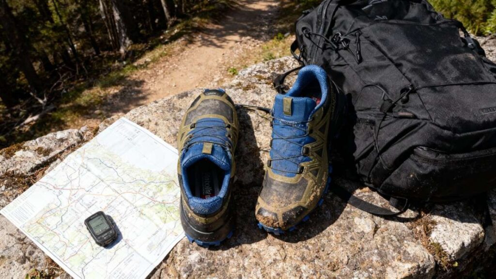 Pair of Salomon Speedcross 5 placed with map & hiking backpack.