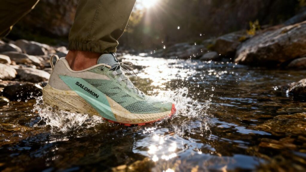 Hiker crossing water stream with Salomon Sense Ride 5.