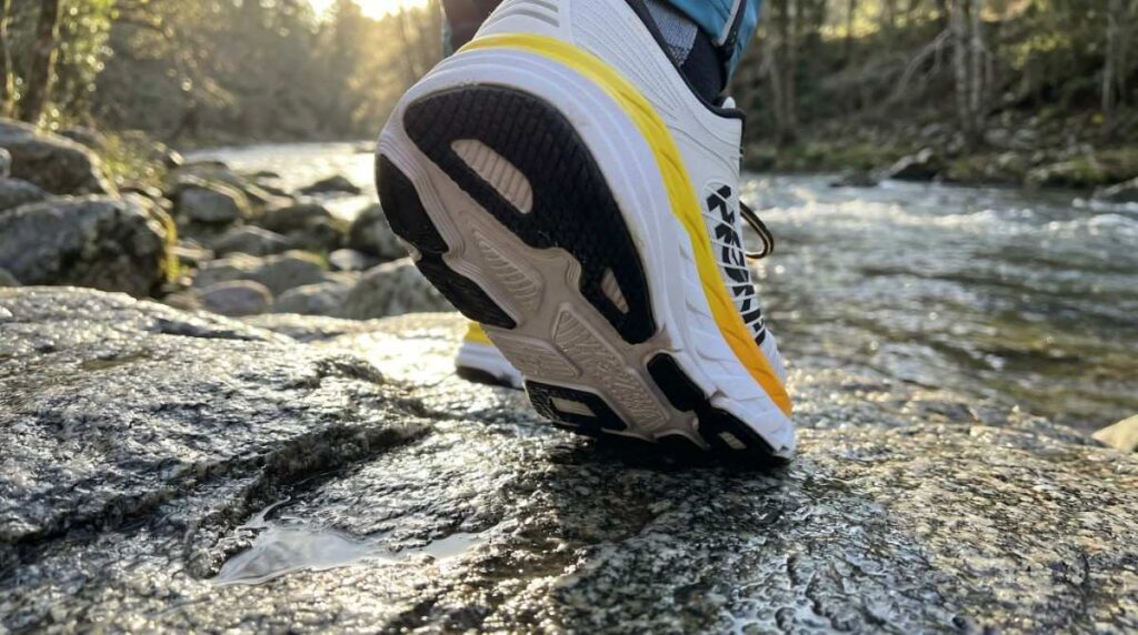 Low-angle shot of Hiker walking on stream side granite rocks. 