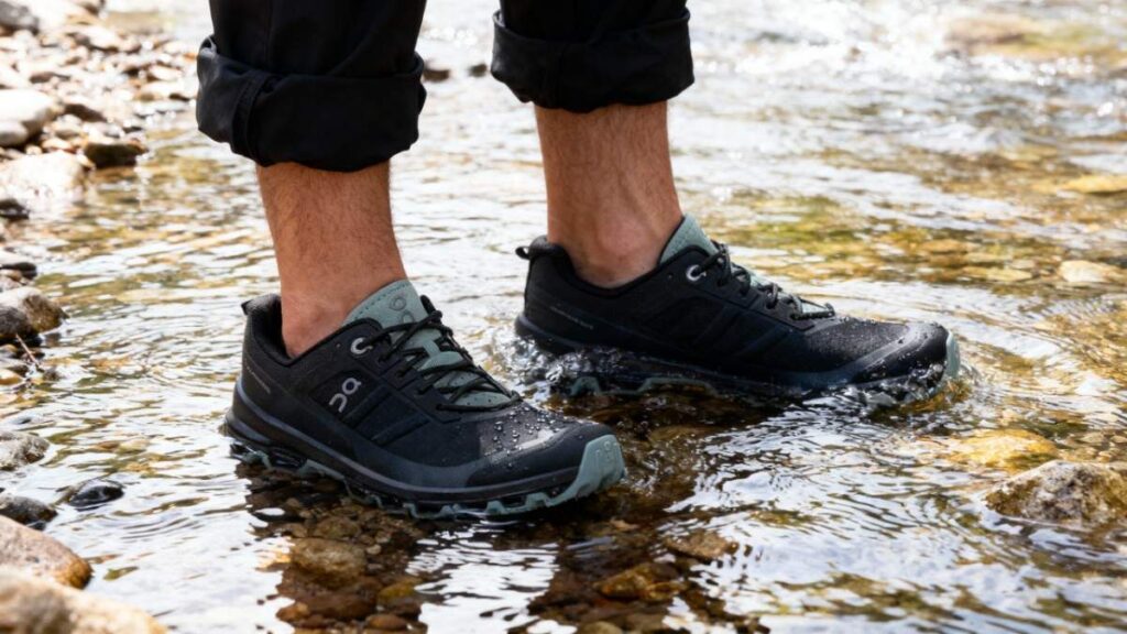 Close-up of hiker wearing On Cloudventure and standing in a water stream.