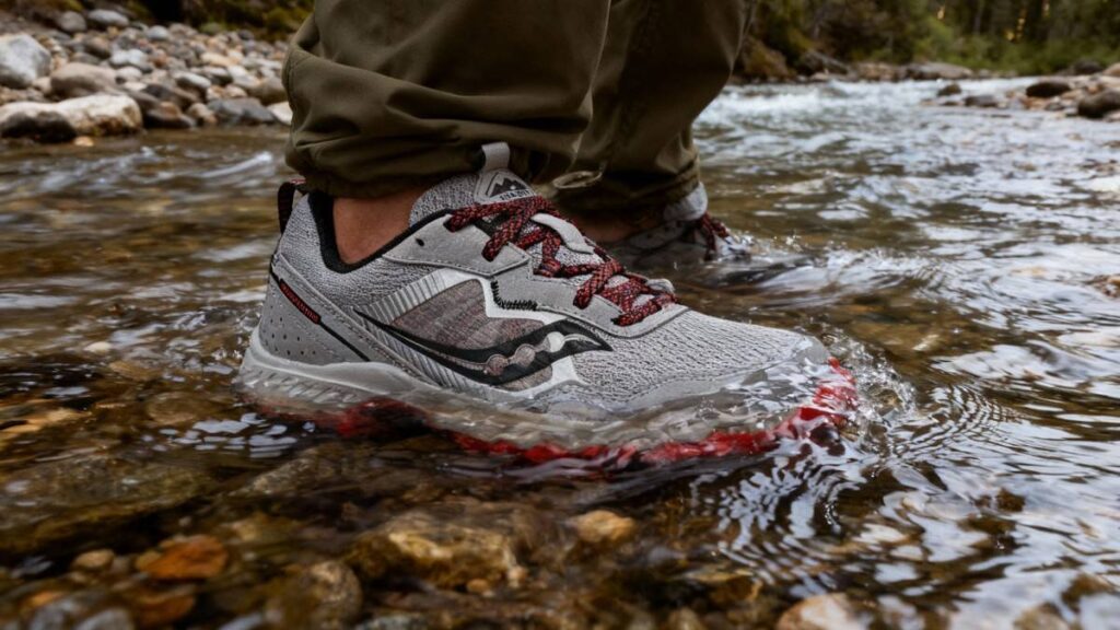 Hiker standing firm in water stream wearing Saucony Excursion TR16.