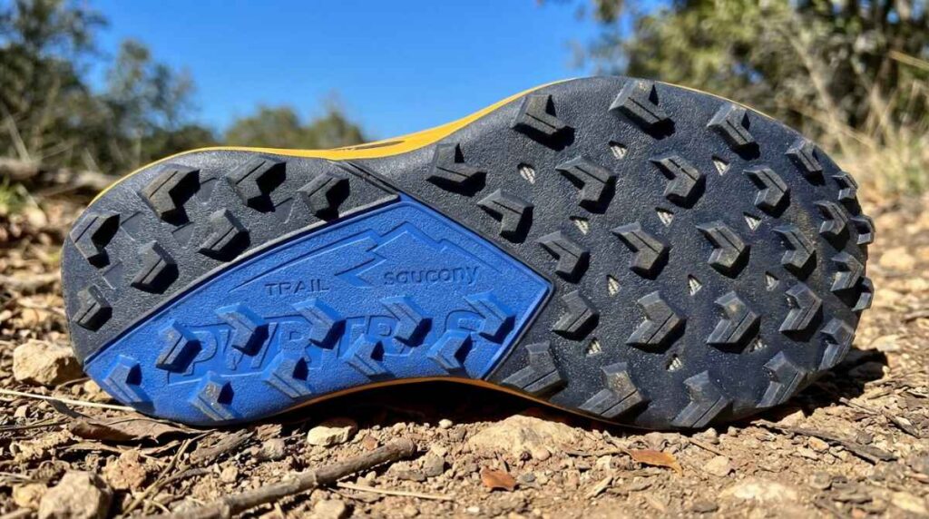 Outsole of Saucony Peregrine 15 placed on an outdoor trail. 